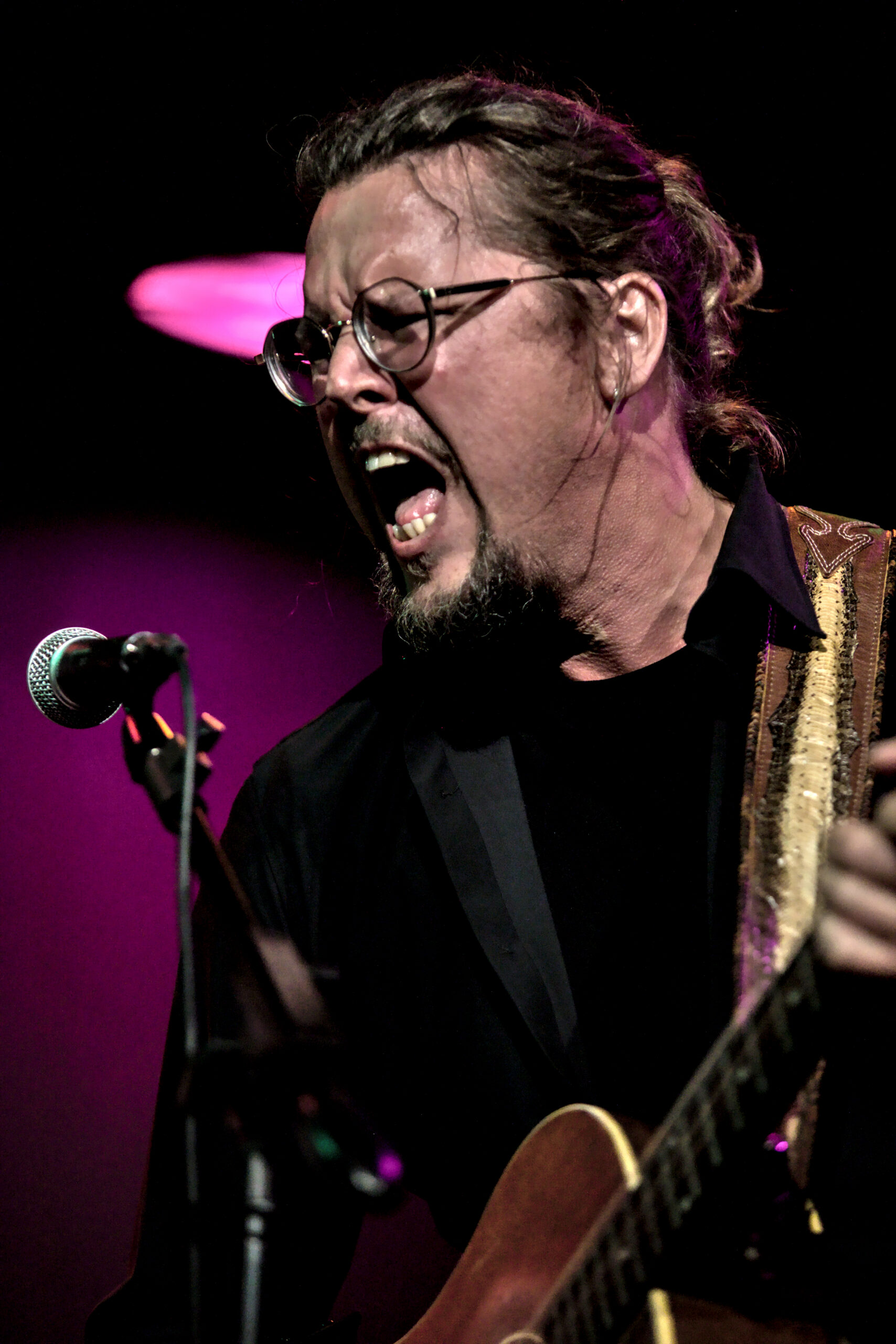 Intense concertfoto van een zingende gitarist met bril tijdens een live optreden op het podium - Matt West Visuals